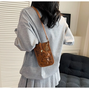 Detailed view of the brown bear pattern crossbody bag worn by a model in casual wear