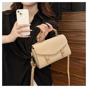 Close-up of beige woven texture shoulder bag with leather handles on a wooden staircase