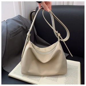 Close-up of a cream nylon crescent tote bag with silver zipper and city lifestyle props