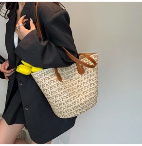 Dettaglio della borsa tote in paglia intrecciata con manici in pelle e trama geometrica