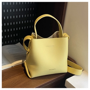 Close-up of lychee grain leather texture and brand logo on yellow bucket bag