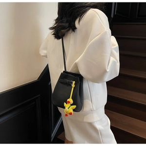 Detailed back view of a black lychee leather bucket bag with a yellow duck charm