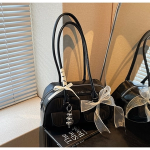 Close-up of black glossy bowling bag with white lace bow and silver heart charms