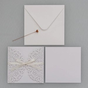 Détail d'une invitation de mariage découpée au laser avec dentelle et décoration en ruban
