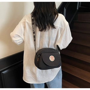 Detailed back view of a black nylon crossbody bag with logo and patterned strap