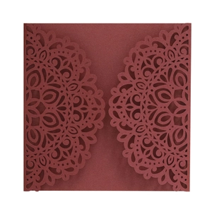 Detail of laser-cut burgundy invitation cover with intricate mandala floral patterns