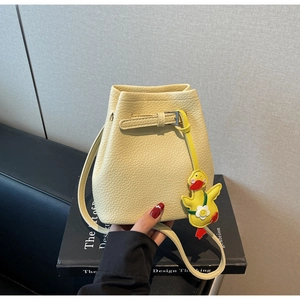 Close-up of cream lychee texture bucket bag featuring a cute yellow duck charm