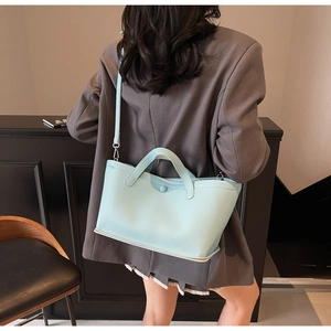 Detail of mint green lychee leather bucket bag with winged design and matching strap