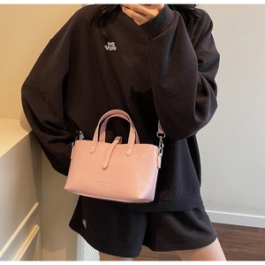 Pink textured faux leather crossbody bag styled with casual grey streetwear outfit