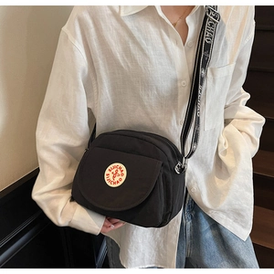 Close-up of black nylon crossbody bag with logo detail and wide jacquard strap