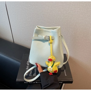 Detail of mint green bucket bag with lychee grain texture and yellow duck charm