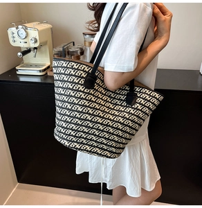 Vista dettagliata della grande borsa tote intrecciata con tracolle in pelle nera sulla spalla