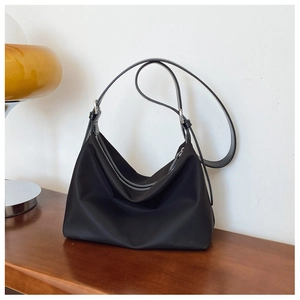 Detail view of black nylon tote bag with adjustable shoulder strap and silver hardware