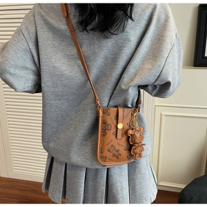 Detail of a brown PU crossbody phone bag with cute cartoon bear prints and charm