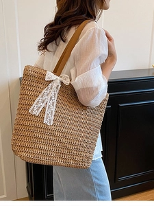 Large straw woven tote bag with white lace bow and brown leather shoulder straps