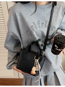 Mini borsa a secchiello nera con motivo trapuntato P e ciondoli indossata a tracolla