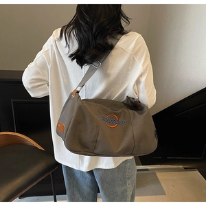 Détail du sac cabas en toile gris foncé avec logo brodé orange et large bandoulière