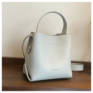 Close-up of light gray bucket bag showing litchi grain texture and silver handle details