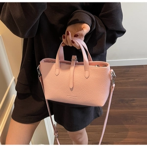 Detail of pink faux leather crossbody bag with ostrich texture and slim shoulder strap