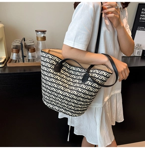 Dettaglio della borsa tote intrecciata bianca e nera con manici in pelle e motivi
