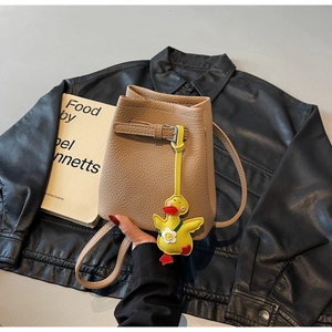 Detailed view of lychee pattern leather bucket bag with a cute yellow duck pendant