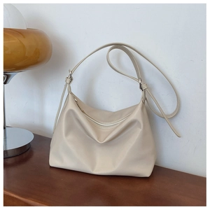 Detail of beige hobo shoulder bag with soft leather texture and adjustable strap on wood