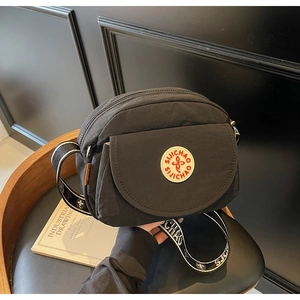 Close-up of black nylon crossbody bag with adjustable strap on a vintage chair
