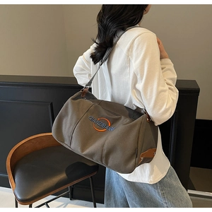Détail du sac bandoulière en toile taupe avec broderie QIANZIBAIGE et finitions en cuir