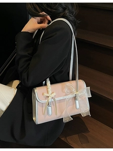 Pink bow shoulder bag with silver trim shown on model at a wooden staircase