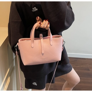 Close-up of pink crocodile texture handbag with adjustable strap and twin handles