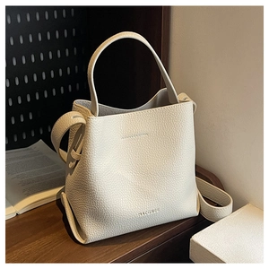Macro detail of lychee pattern leather bucket bag with top handle and brand embossing