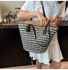 Dettaglio della borsa tote intrecciata a righe bianche e nere con manici in pelle
