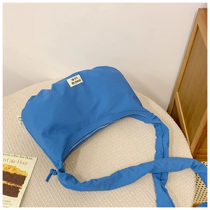Detailaufnahme der Kleinblauen Falten-Nylon-Tasche mit strukturiertem Gurt und Markenetikett