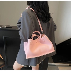 Side view of pink pebbled leather bucket bag with top handle and adjustable strap