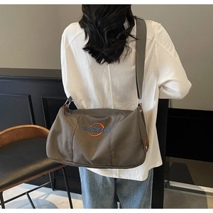 Détail du sac cabas en toile grise avec logo brodé et large bandoulière réglable