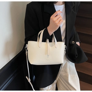 Detail of cream white textured tote bag with FASHION BAG logo and adjustable shoulder strap