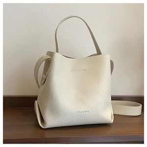 Detailed close-up of cream-white litchi grain leather and embossed logo on bucket bag