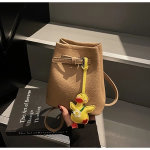 Detail of lychee pattern bucket bag in camel with cute yellow duck pendant accessory