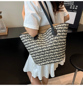 Dettaglio della borsa tote in paglia intrecciata con spalline in pelle nera