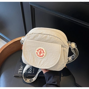 Detail of off-white nylon crossbody bag showing pleated texture and wide branded strap