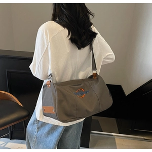 Vue arrière du modèle portant un sac polochon en toile grise avec garniture en cuir