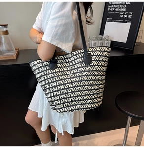 Dettaglio della borsa tote intrecciata con motivi geometrici bianchi e neri e manici in pelle