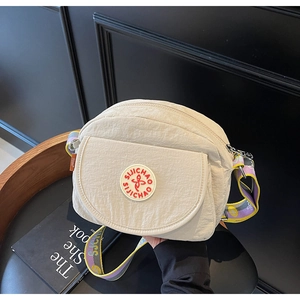 Detail of beige nylon crossbody bag with red logo and colorful jacquard patterned strap