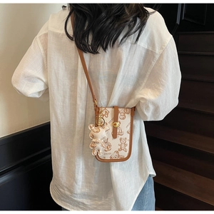 Rear view of a small crossbody phone bag with teddy bear print and brown shoulder strap