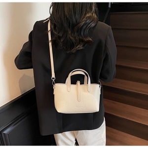 Detail view of cream pebble leather mini tote bag with adjustable shoulder strap and handle