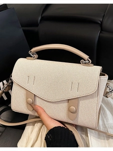 Beige crossbody bag with textured fabric flap and dual strap design for daily commute