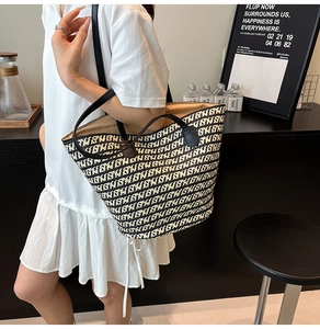 Dettaglio borsa tote intrecciata con motivi geometrici bianco nero e manici in pelle