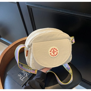Detail of beige nylon round crossbody bag with jacquard logo strap on a chair