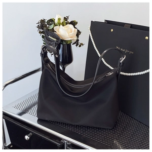 Fashionable black nylon crescent shoulder bag with silver hardware on a modern prop display