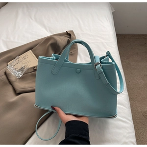 Detail of light blue lychee pattern leather tote bag with stylish side metal buckle